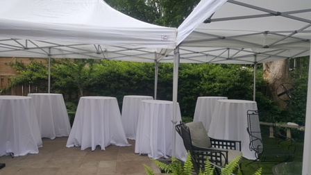 7 30inch round cruiser tables with 120inch round tablecloths on them under 2 10 foot by 20 foot white pop up tents in backyard of home in Etobicoke
